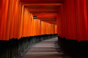 Gray concrete pathway between red and black pillars in Kyoto, Japan