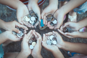 Young people's hands in a circle filled with coins