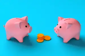 Two piggy banks facing each other with a pile of coins between them