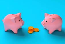 Two piggy banks facing each other with a pile of coins between them