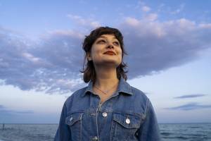 A woman looking up with the sea and sky in the background