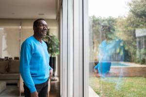 Man looking out the window, with his reflection visible in the glass