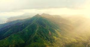 Large mountain range with sun shining and clouds above