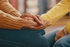 Two people sitting across from each other with hands clasped