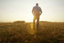 Man walking up a hill with sunlight streaming toward him