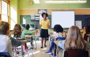 Teacher standing in front of middle school class seated in their desks