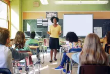 Teacher standing in front of middle school class seated in their desks