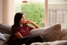 Teen sitting on the couch looking off to the side