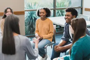 Group of Black and white students sitting in a circle with a teacher