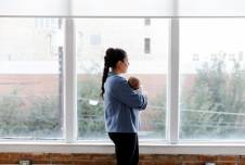 Mom standing holding her baby in front of a set of windows