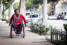 Woman smiling in a wheelchair on a sidewalk
