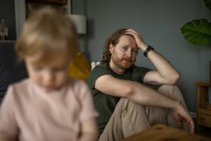 Father in the background looking worried at his daughter in the foreground