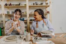 Two women doing pottery and smiling at each other