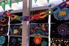 Classroom wall with flags, a chain of gratitude notes, and art. 