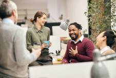 Group of coworkers sitting around drinking coffee and laughing