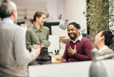 Group of coworkers sitting around drinking coffee and laughing