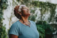 Woman with closed eyes in front of trees