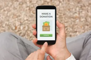 Someone with crossed legs on the floor holding a phone that shows a 