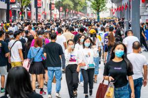 Crowd of people walking outdoors in China, mostly with masks