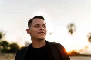 Young man looking up outdoors with setting sun behind him