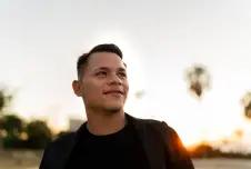 Young man looking up outdoors with setting sun behind him