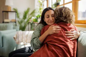 Two women sitting on a couch hugging