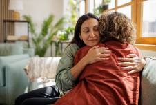 Two women sitting on a couch hugging