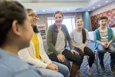 Students sitting in a circle smiling and talking