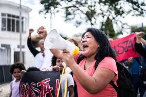 Woman with a megaphone participating in a protest, with other protestors around