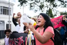 Woman with a megaphone participating in a protest, with other protestors around