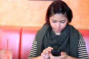 Young woman looking down at her smartphone at a restaurant