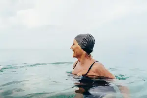 Woman with a swim cap treading water and smiling in the sea
