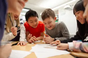 Group of students huddled over a desk smiling