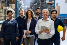 Employees posing for a group photo, smiling, at a warehouse