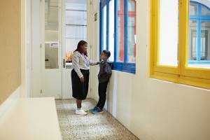 Teacher talking to a student in a corridor with her hand on his shoulder