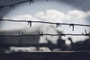 Closeup of barbed wire fence with clouds behind