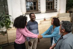 Four neighbors standing together, two of them holding hands in greeting