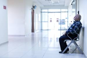 Lone man sitting in a medical waiting area 