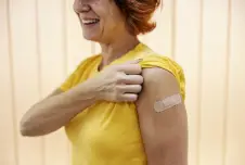 Woman rolling her sleeve up showing a band-aid where she got a vaccine