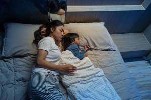 Mother and toddler son sleeping in bed