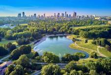 A city in the background with more green landscape and a lake in the foreground