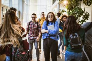 Student frozen looking nervous with other students walking around her at school