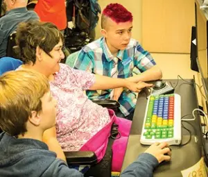 Two students on a computer with an elder