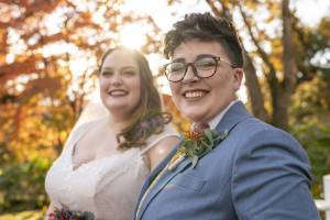 Two brides smiling outdoors on their wedding day