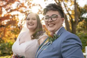 Two brides smiling outdoors on their wedding day