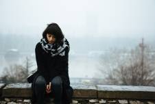 Woman sitting on a wall looking down with fog in the background