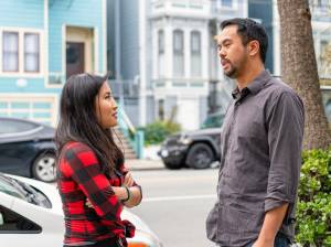 Two people engaged in conversation on the street, one with arms crossed