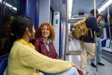 Two women talking on the subway with other passengers in the background