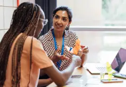 Two teachers sitting and talking next to a laptop