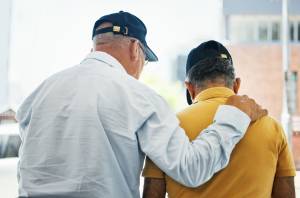 Back view of one man with his arm on another man's shoulder for comforting